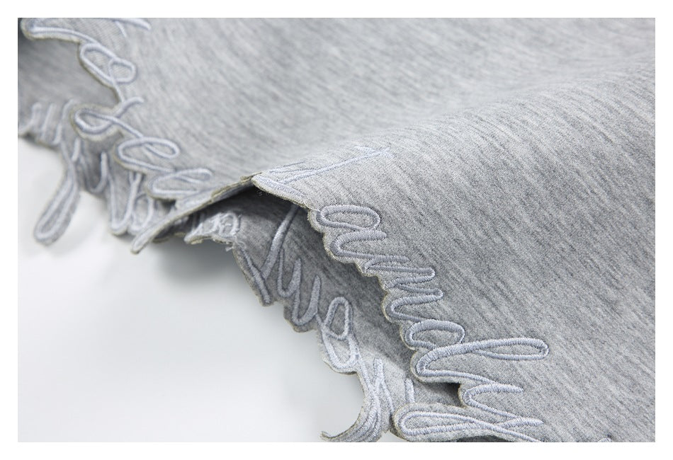 Close-up of raised script embroidery on a gray heather sweatshirt sleeve.