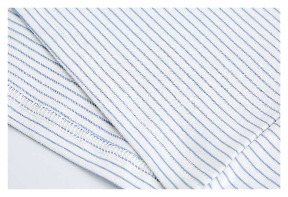 Close-up of white fabric with thin blue stripes and a stitched seam.
