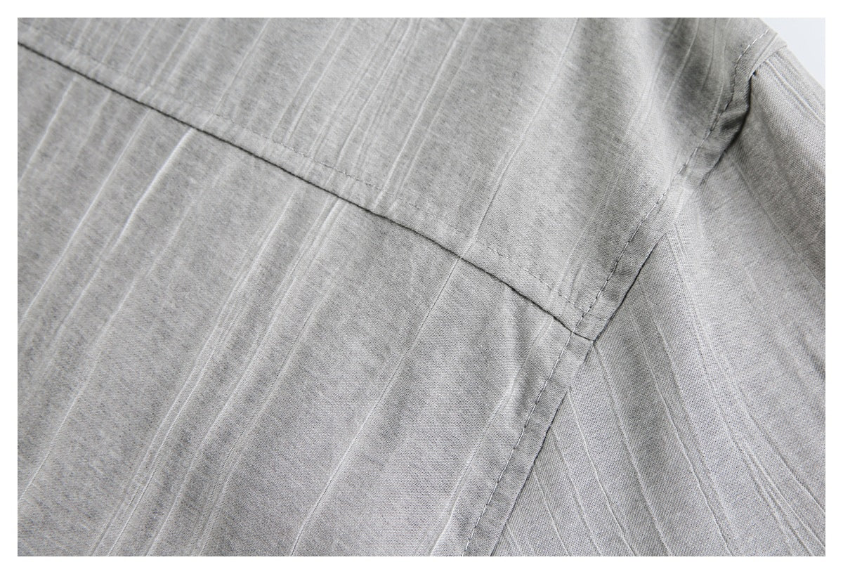 Close-up of gray subtly striped fabric showing intersecting seams and a curved garment edge.
