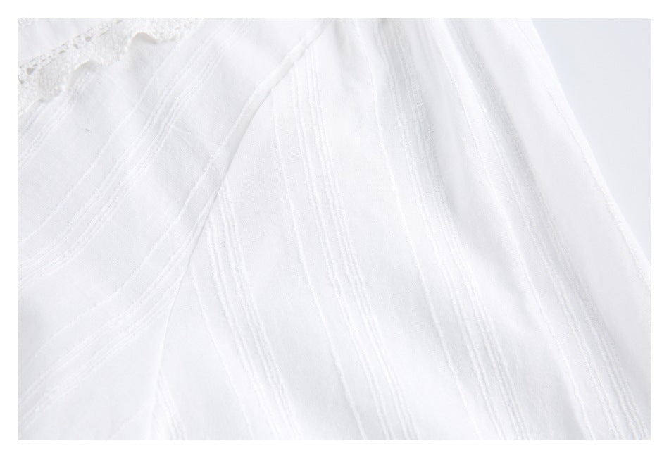 Close-up of white garment fabric with raised stripe detailing, a seam, and a glimpse of lace trim.