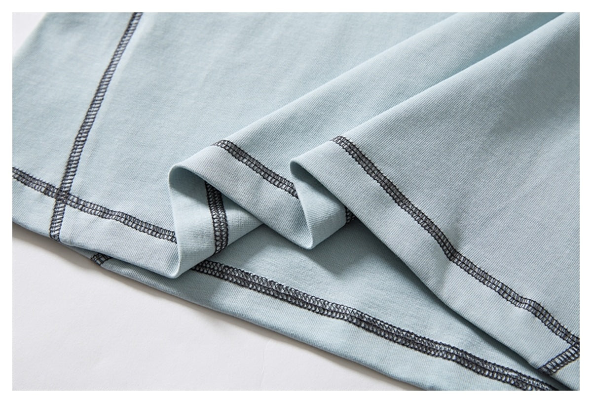 Close-up of the pale blue garment hem, folded to show dark overlock stitching.