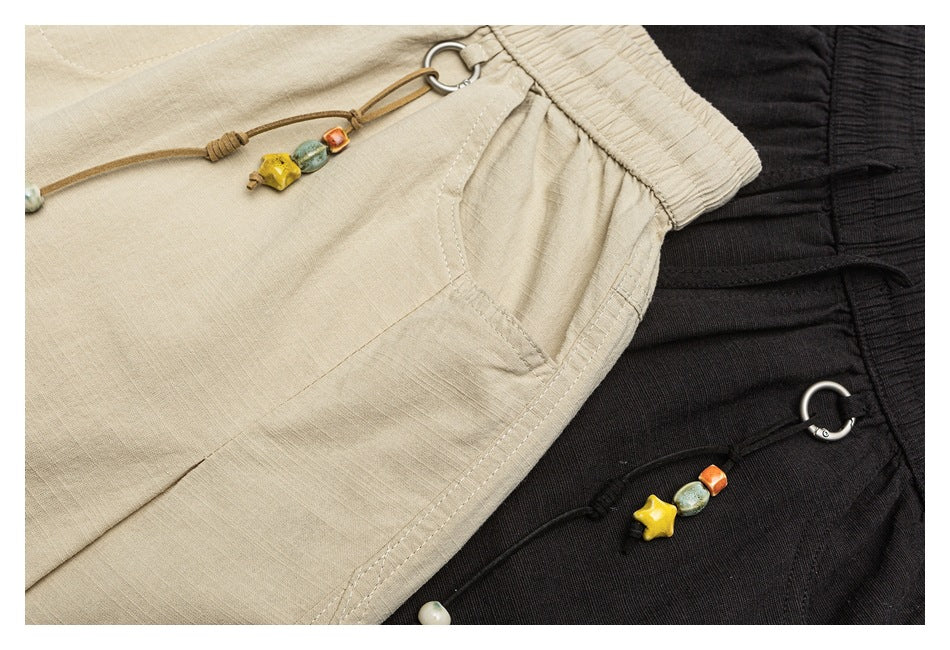 Close-up of beige and black pants showing elastic waistbands, pocket seams and beaded drawcord details.
