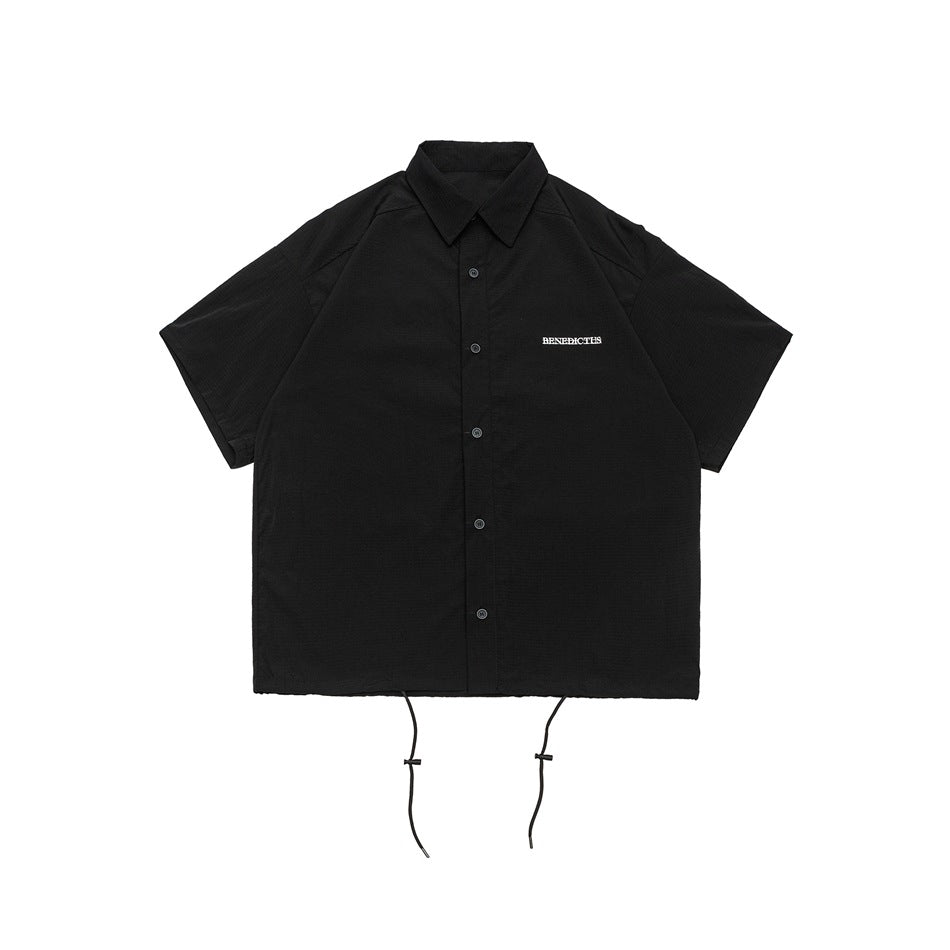 Black short-sleeve button-front shirt with collar, small white chest lettering and drawstring hem, flat lay