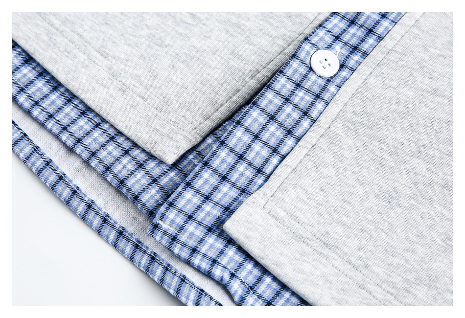 Close-up of a white button on the blue plaid placket against light gray shirt fabric.