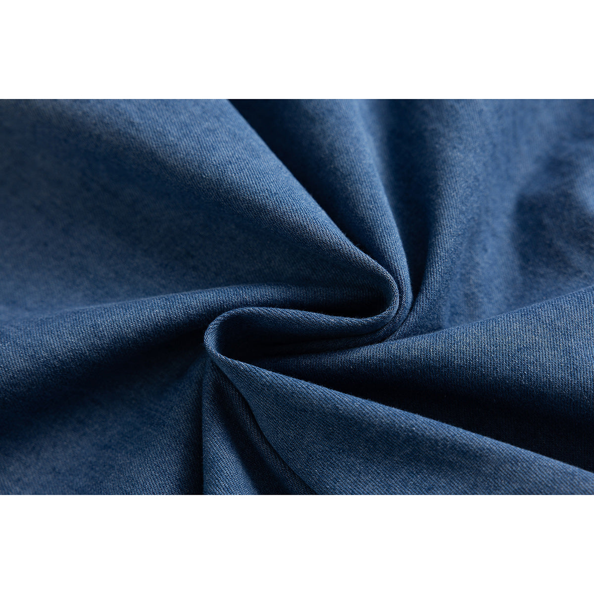 Close-up of dark blue denim fabric gathered into soft folds.