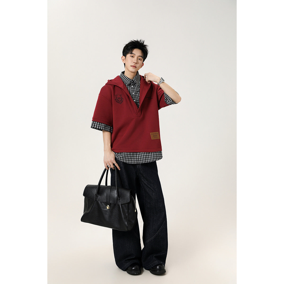 Model wearing a burgundy short-sleeve hooded pullover over a black-and-white checked shirt.