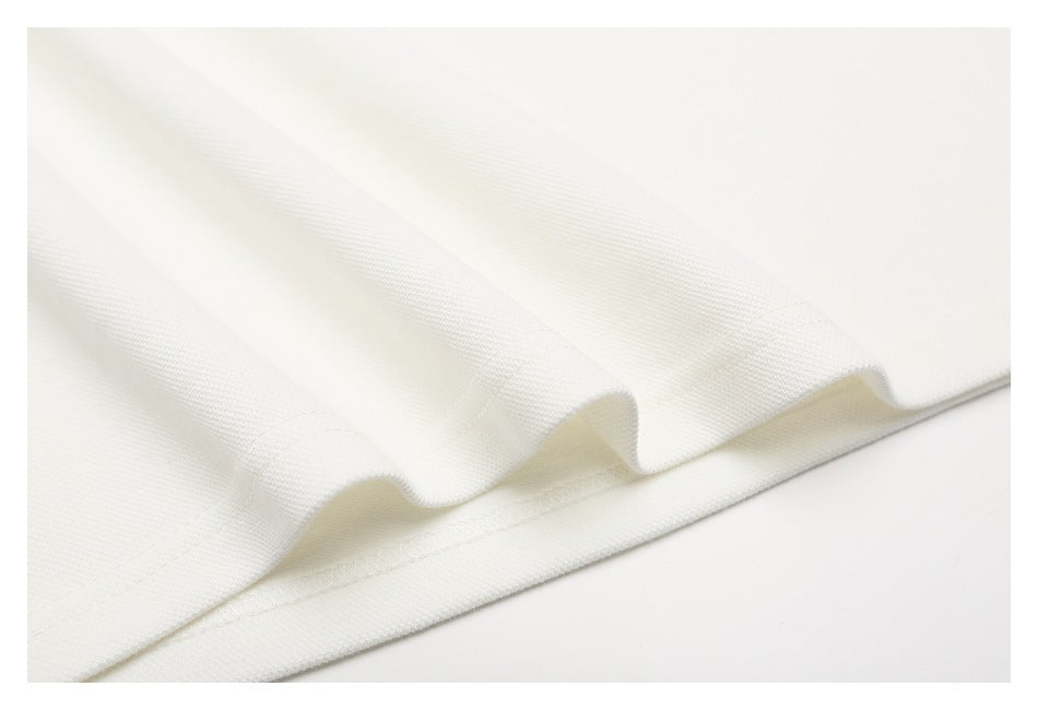 Close-up of the stitched hem on off-white textured polo fabric.