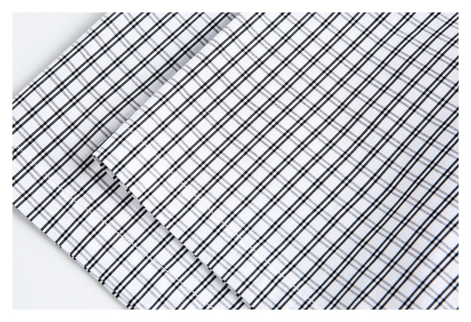 Close-up of overlapping panels of white fabric with a black and gray plaid pattern.