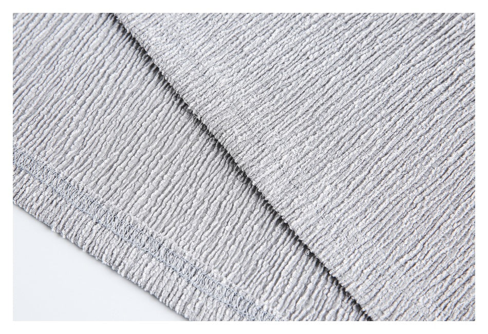 Close-up of the hem stitching and textured fabric on a light gray top.