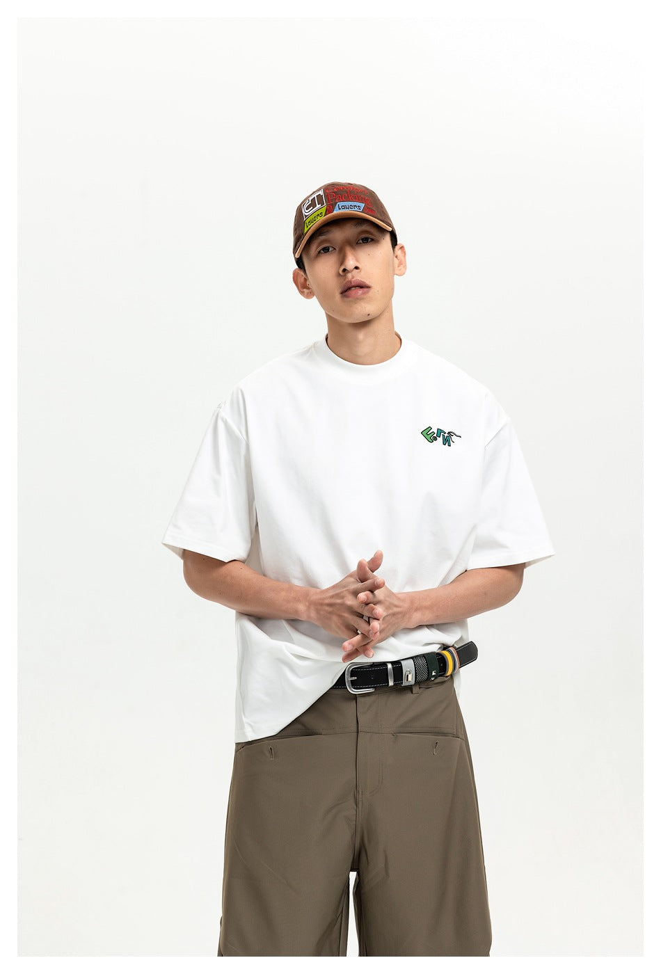 Model wearing a white oversized T-shirt with a small colorful chest graphic; front view.