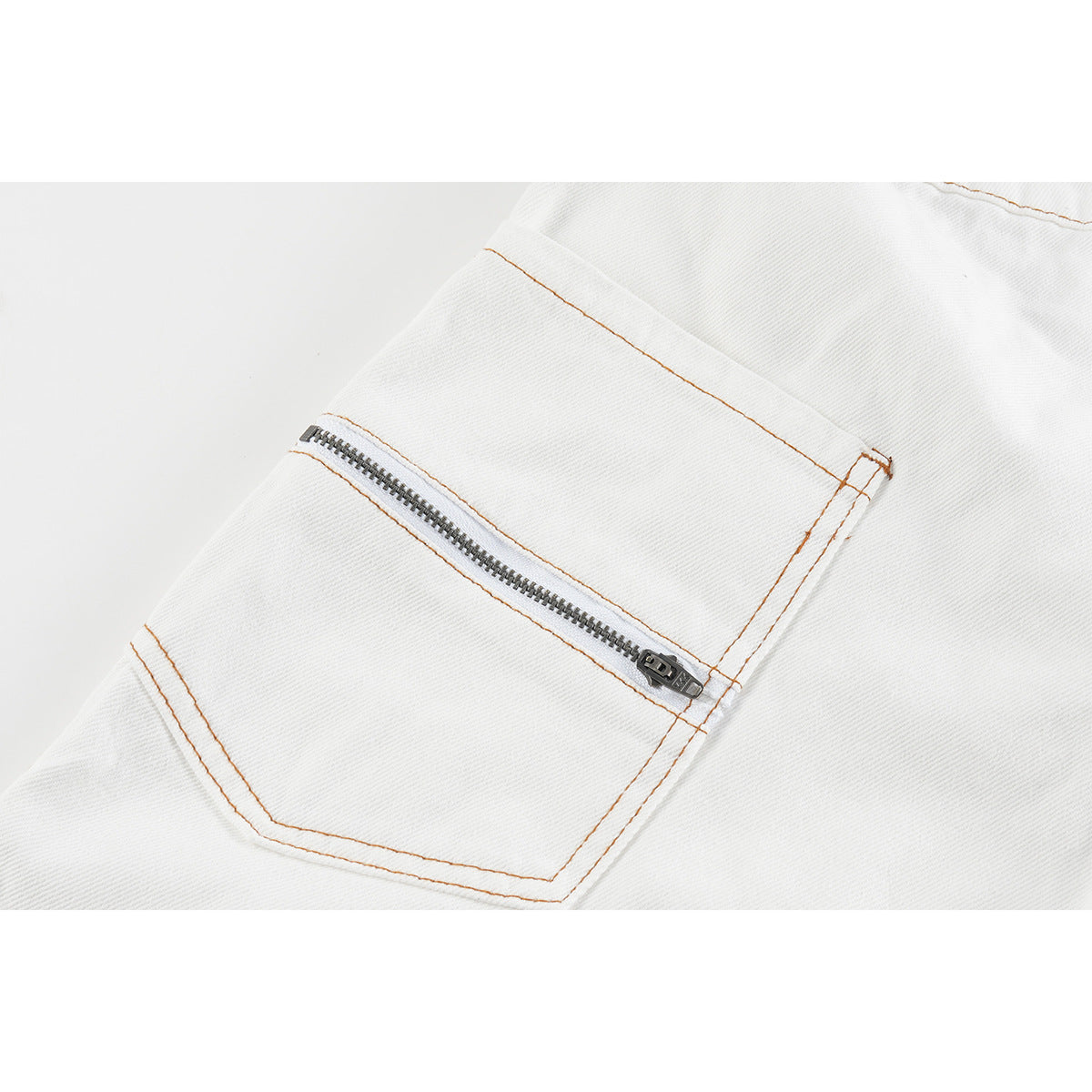 Close-up of a zippered pocket on white denim shorts, outlined with orange-brown stitching.