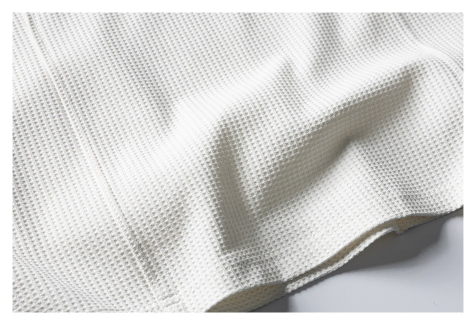 Close-up of the ivory waffle-knit texture and finished garment edge.