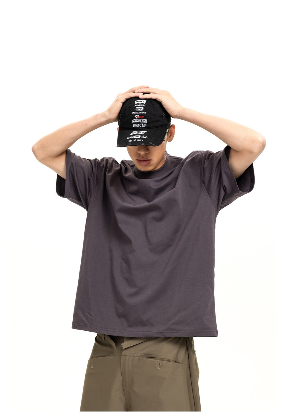 Closer front view of a model wearing a plain charcoal oversized T-shirt with olive trousers.