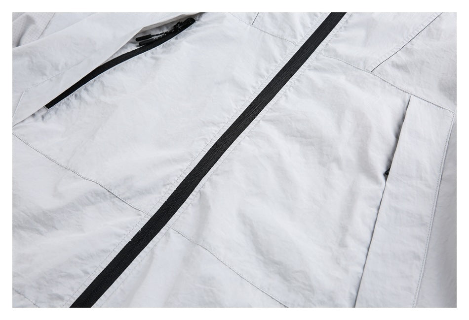 Close-up of a light gray jacket front with a black center zipper and a diagonal zip pocket.