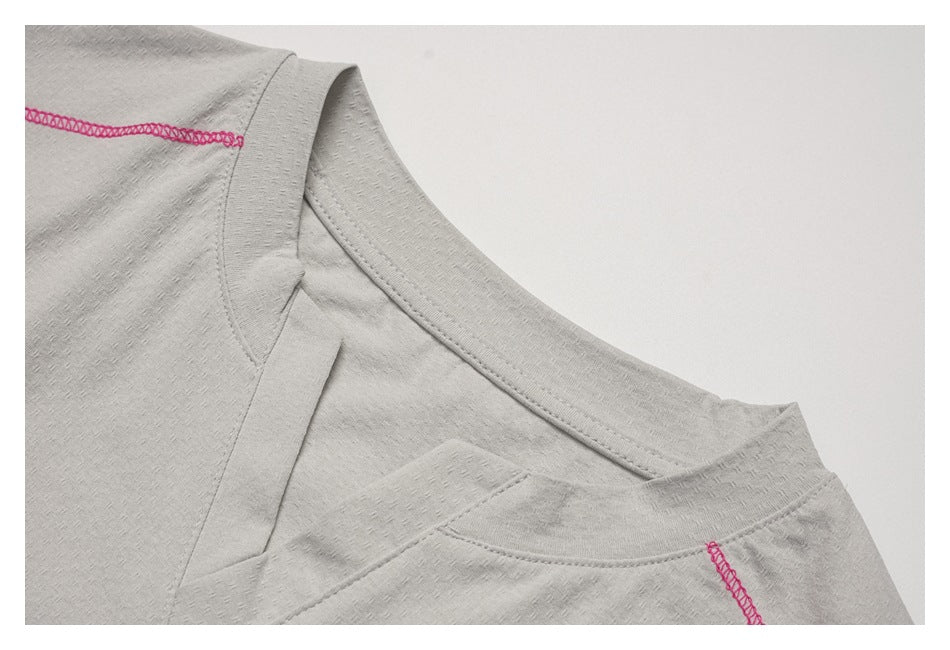 Close-up of the light gray top's crew neckline and shoulder seams with bright pink overlock stitching.