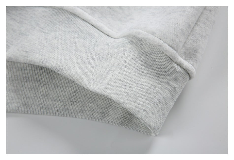 Close-up of the light gray marled jacket's ribbed hem band and seam.