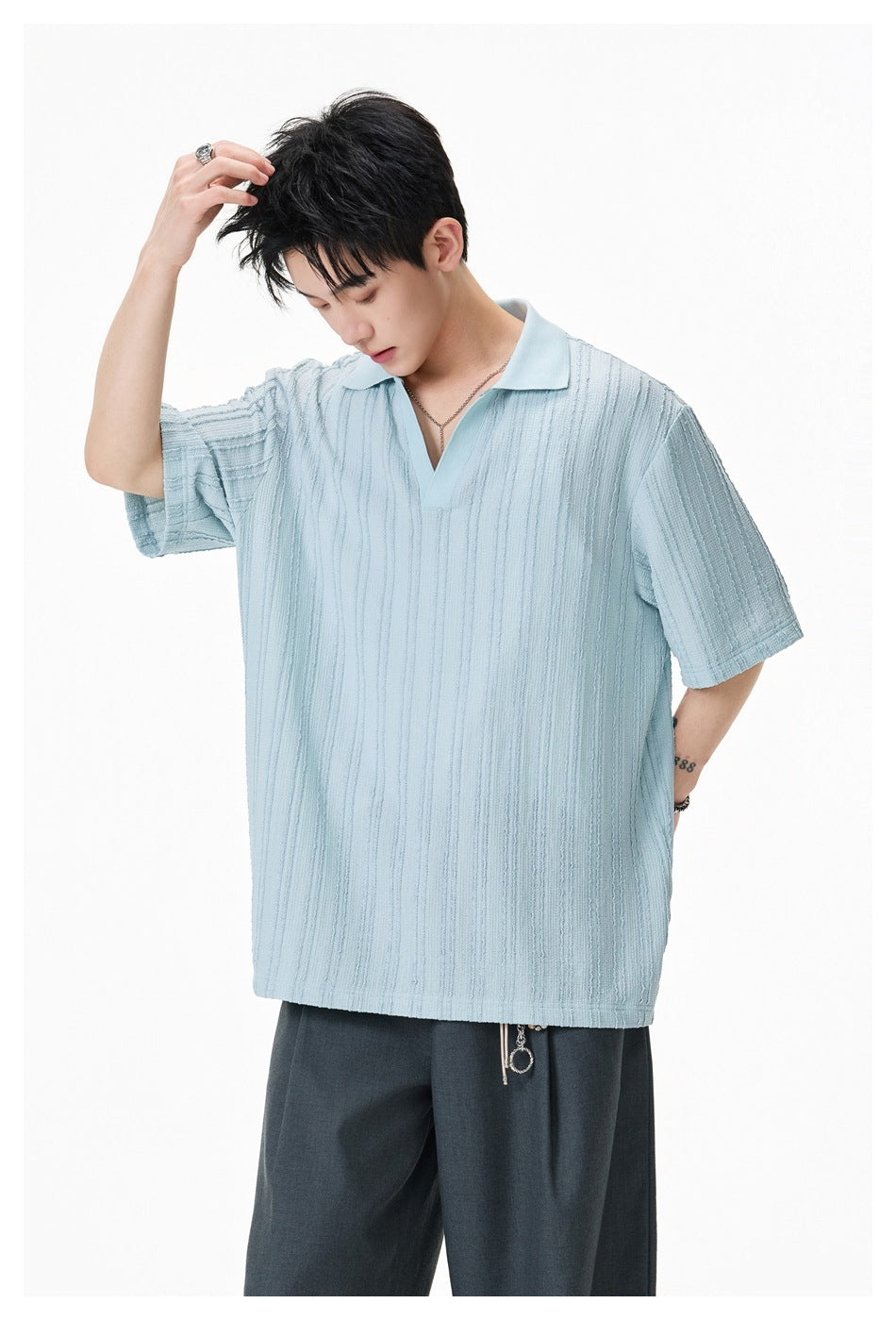 Close three-quarter view of a model in a sky blue textured-stripe short-sleeve polo top with open V-neck