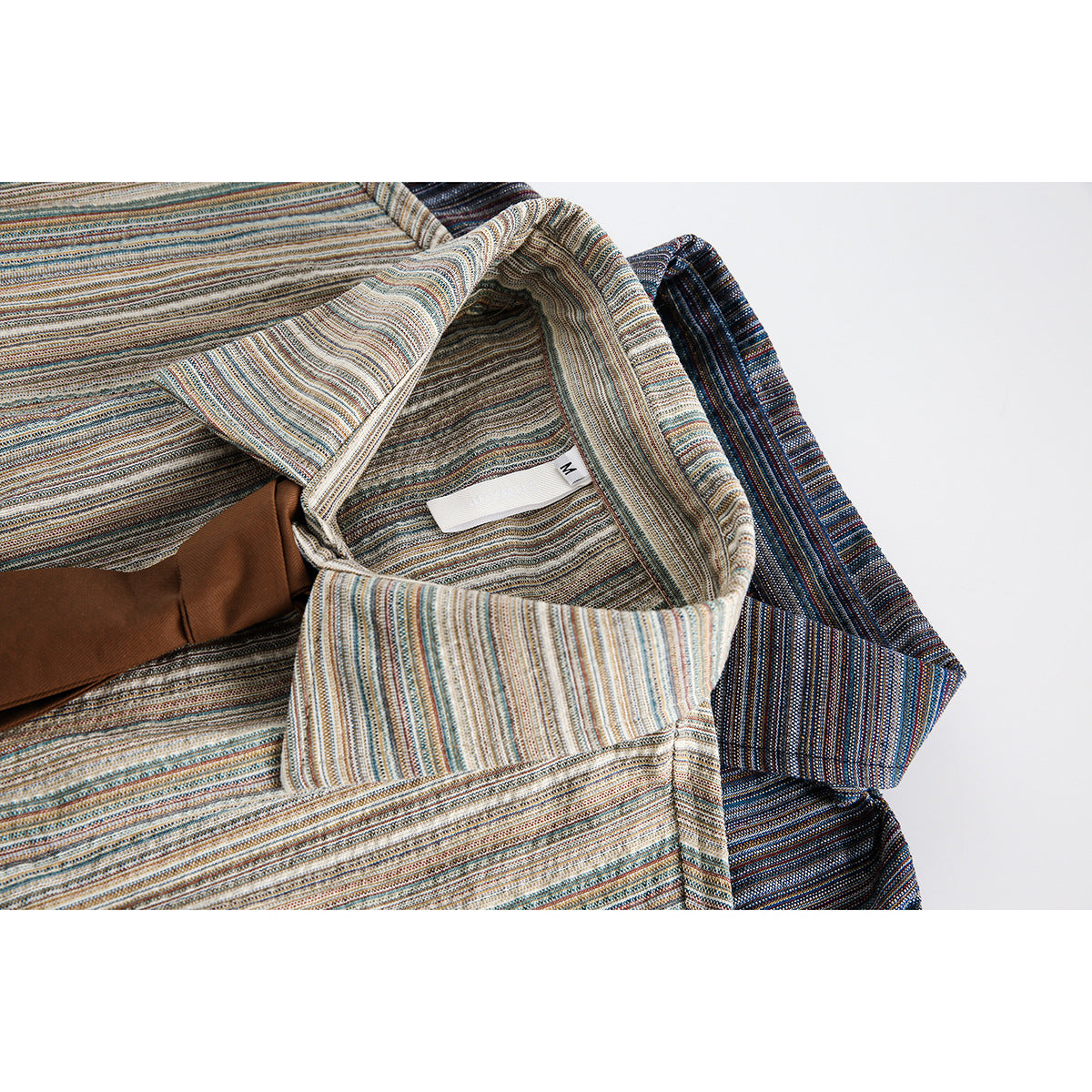 Close-up of a light multicolor striped shirt collar, inner label, and brown tie.