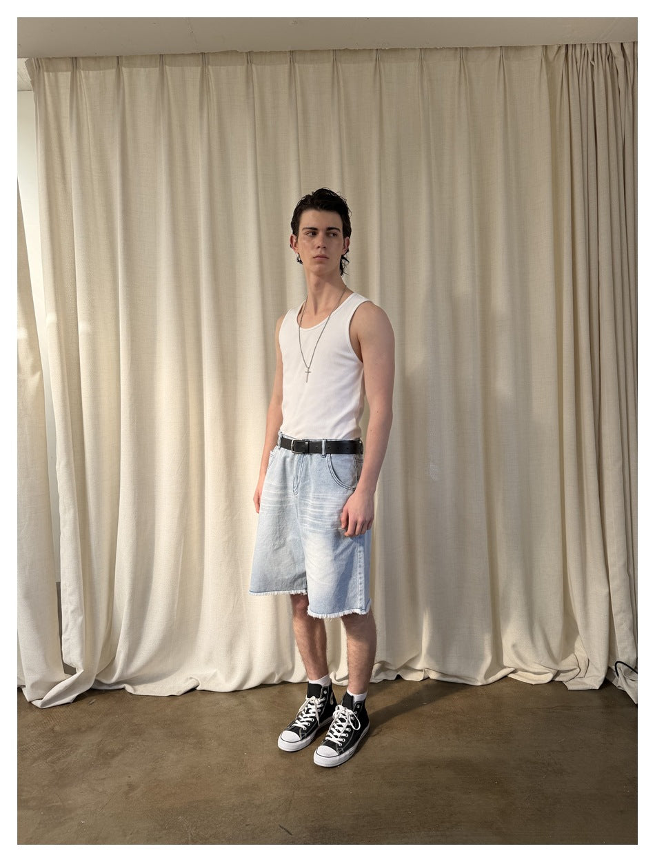 Model in light blue denim shorts with frayed hem, white tank top and black high-top sneakers, three-quarter view