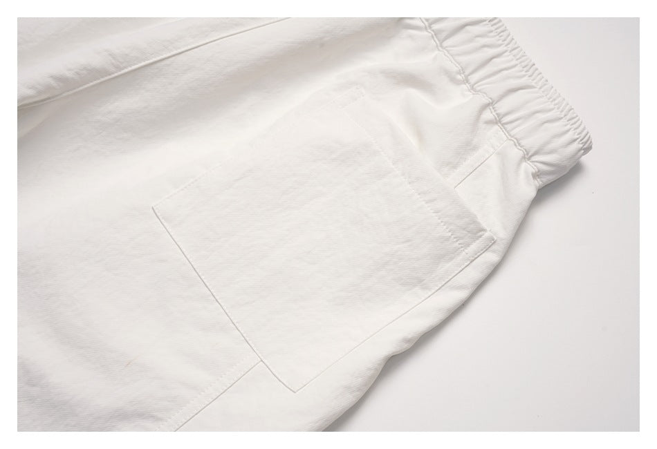 Close-up of an off-white pants back pocket, stitching, and gathered elastic waistband.