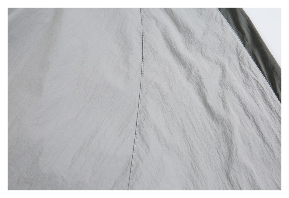 Close-up of a vertical stitched seam on light gray fabric, with a dark gray panel visible at the edge.