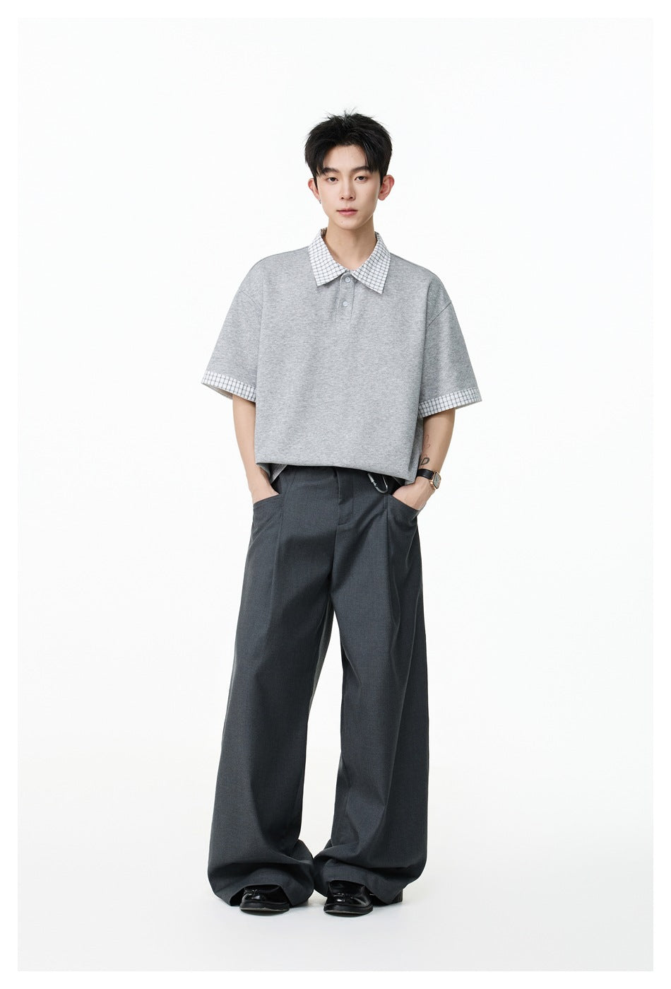 Model standing in a heather gray plaid-trim polo with gray wide-leg trousers and black loafers
