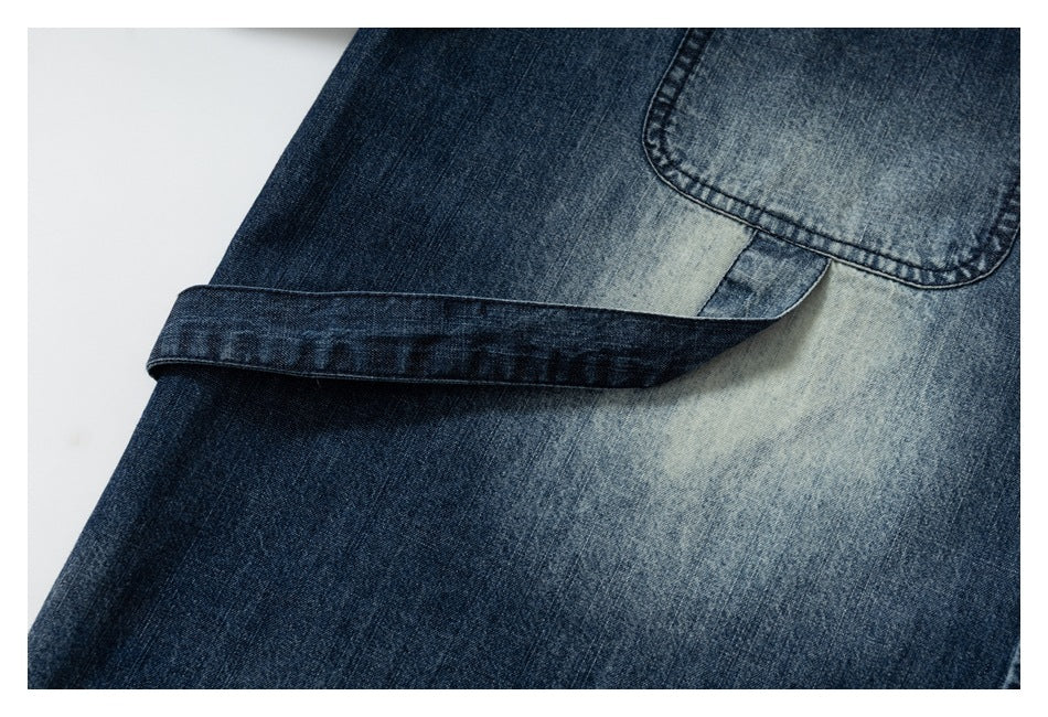 Close-up of a faded blue denim pocket and overlapping stitched fabric flap.
