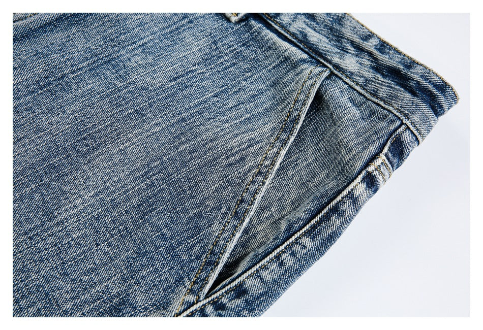 Close-up of faded blue denim with a long stitched seam and the edge of a pocket.