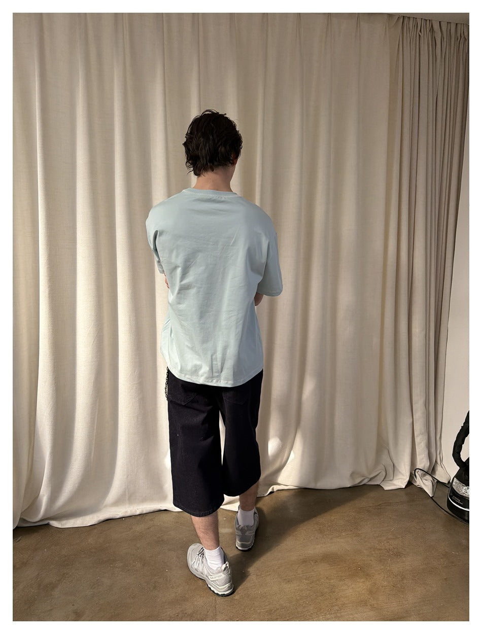 Rear view of a model wearing a plain pale blue T-shirt and black shorts.