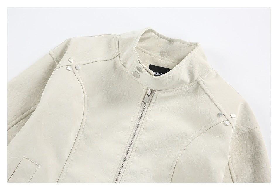 Close-up of an ivory jacket front showing the stand collar, zipper, curved seams and snap accents.