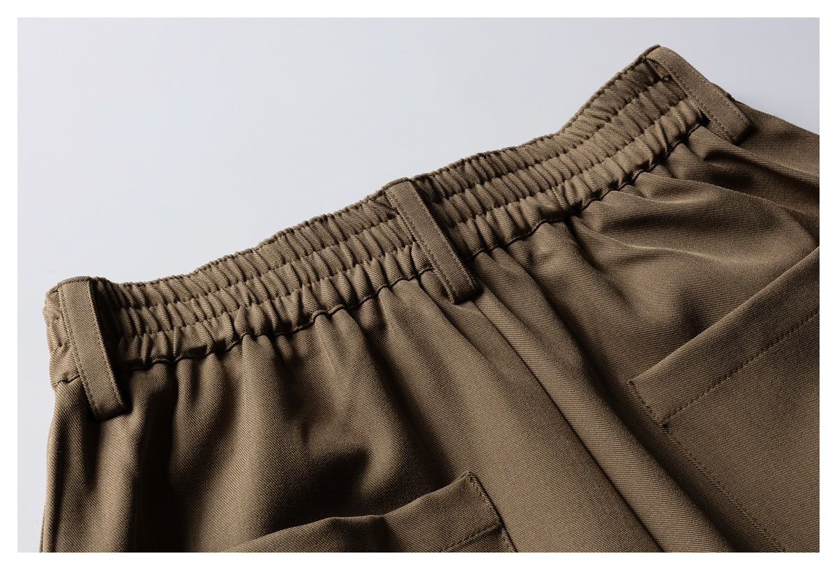 Close-up of brown trousers showing an elastic waistband, belt loops, and pocket openings.