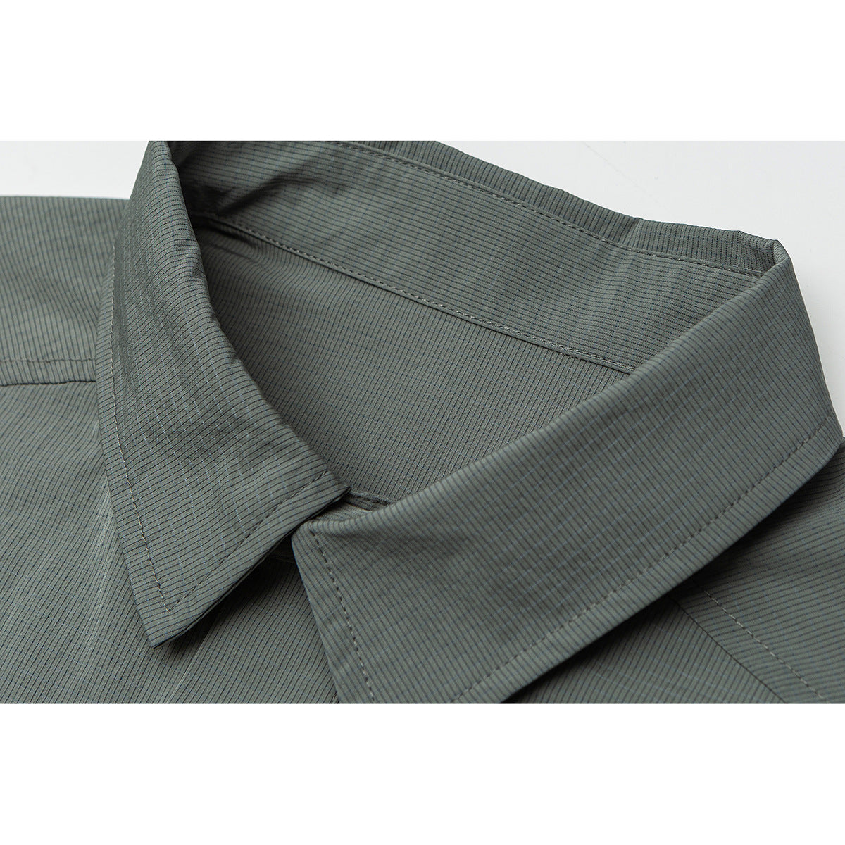 Close-up of a gray-green shirt's pointed collar, showing fine vertical striping and stitched seams.