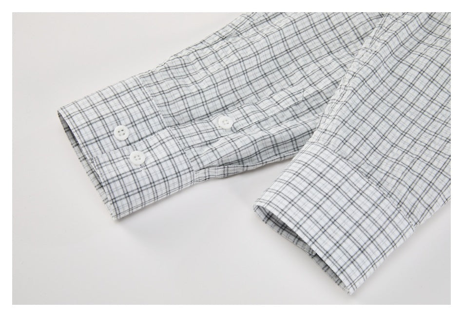 Close-up of a gray-plaid shirt sleeve and buttoned cuff on a white background.