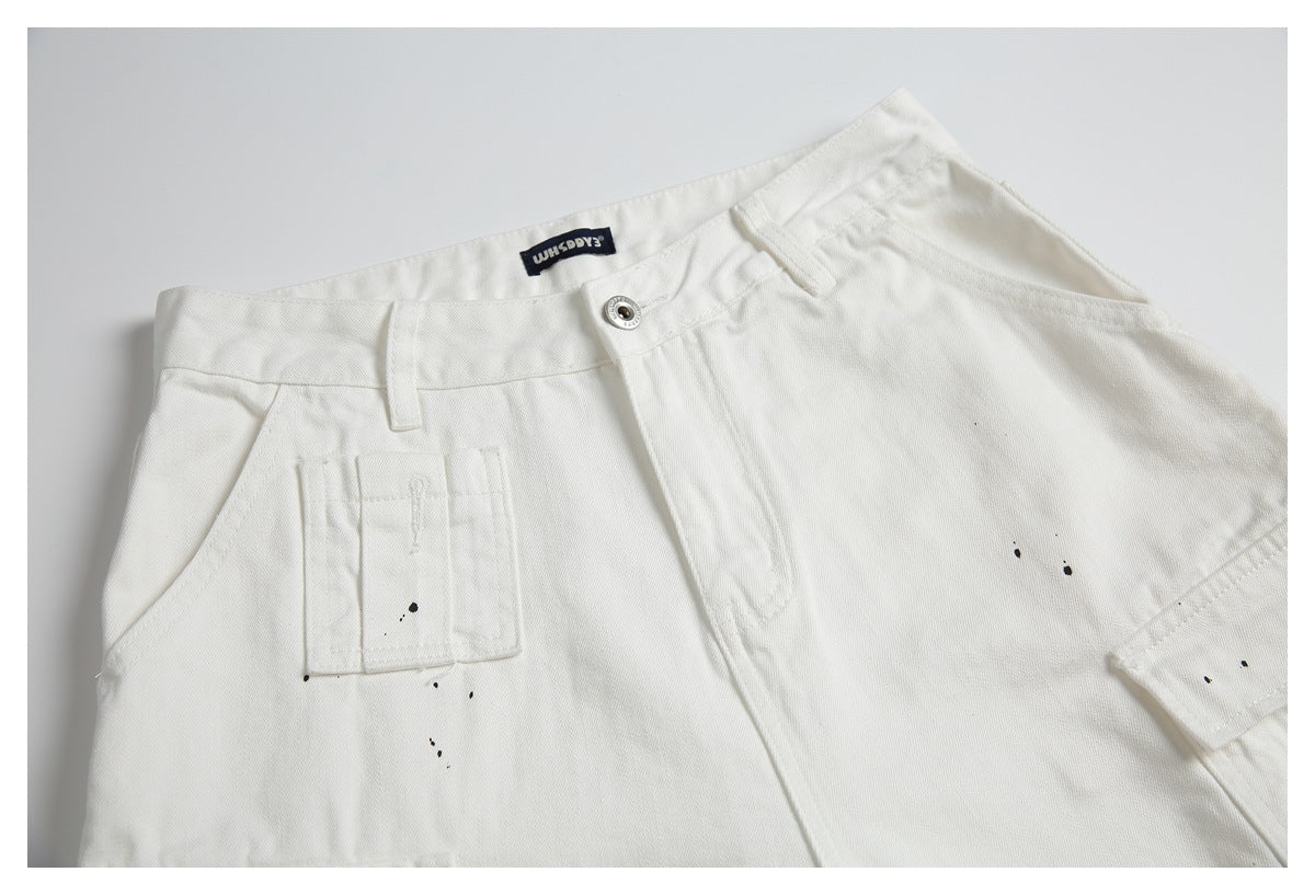 White pants shown from the front, with a button waist, utility pocket, and scattered black specks.