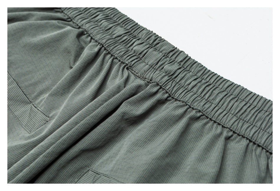 Close-up of the gathered elastic waistband and stitched pocket opening on a blue-gray striped garment.