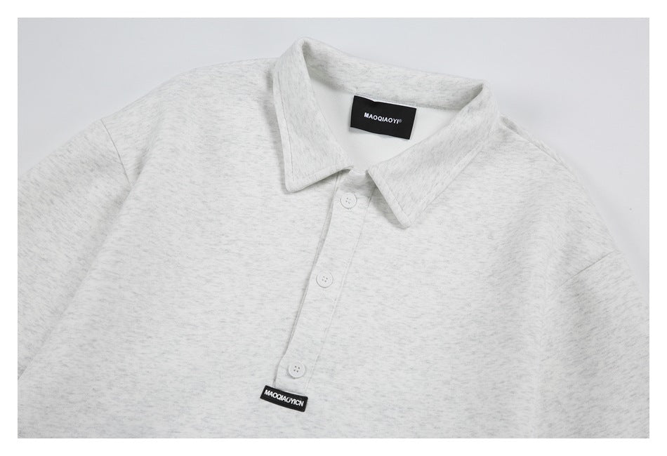 Close view of a light gray heather collared shirt with a three-button placket, laid flat.