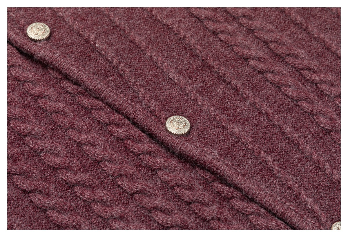 Close-up of a burgundy cable-knit garment with ornate round metallic buttons.