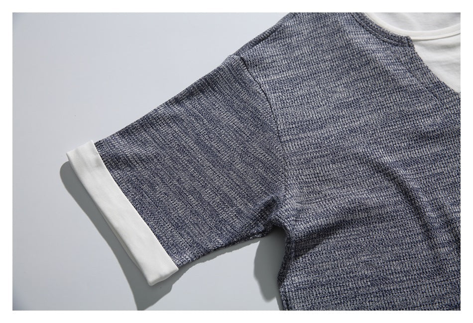 Close-up of a short sleeve with a wide white cuff on the gray-blue textured top.