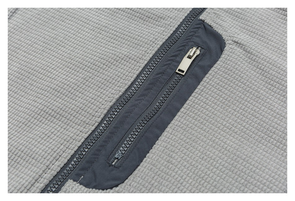 Close-up of a slim zip pocket set into a dark panel on gray textured fabric.