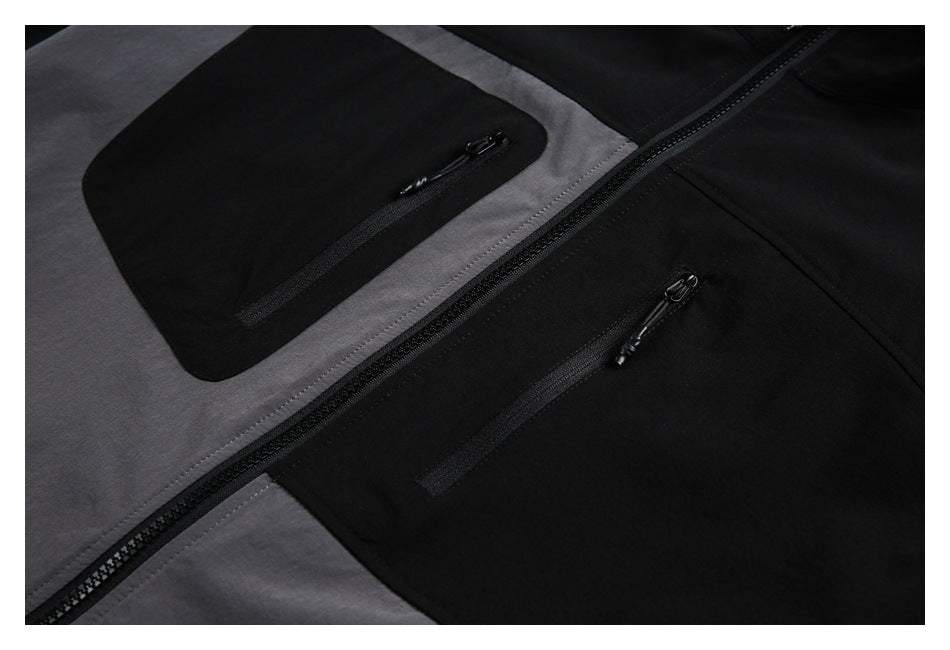 Close-up of the jacket's black zippered chest pockets and central zipper against gray and black panels.