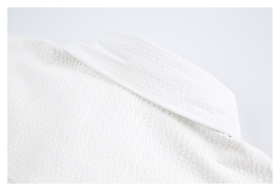 Close-up of the pointed collar on a white textured shirt.