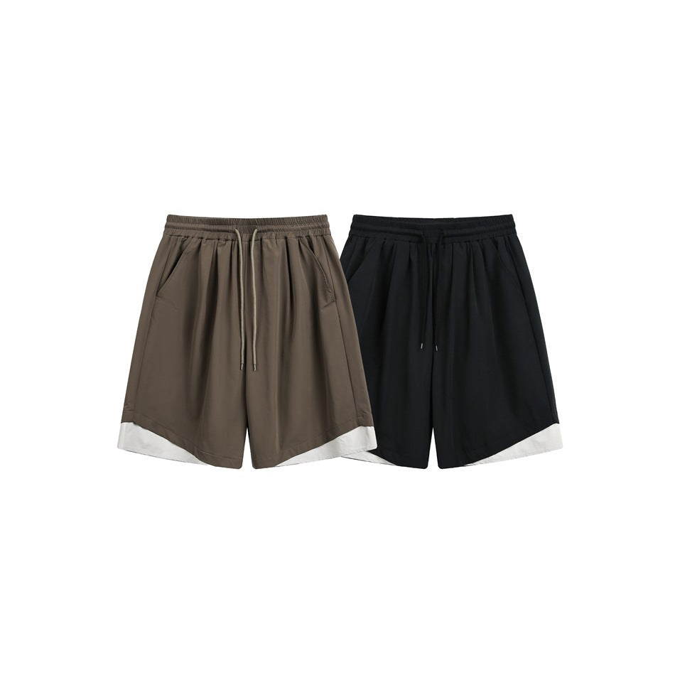 Front view of taupe and black shorts with elastic drawstring waists, side pockets, and contrasting off-white hem panels.