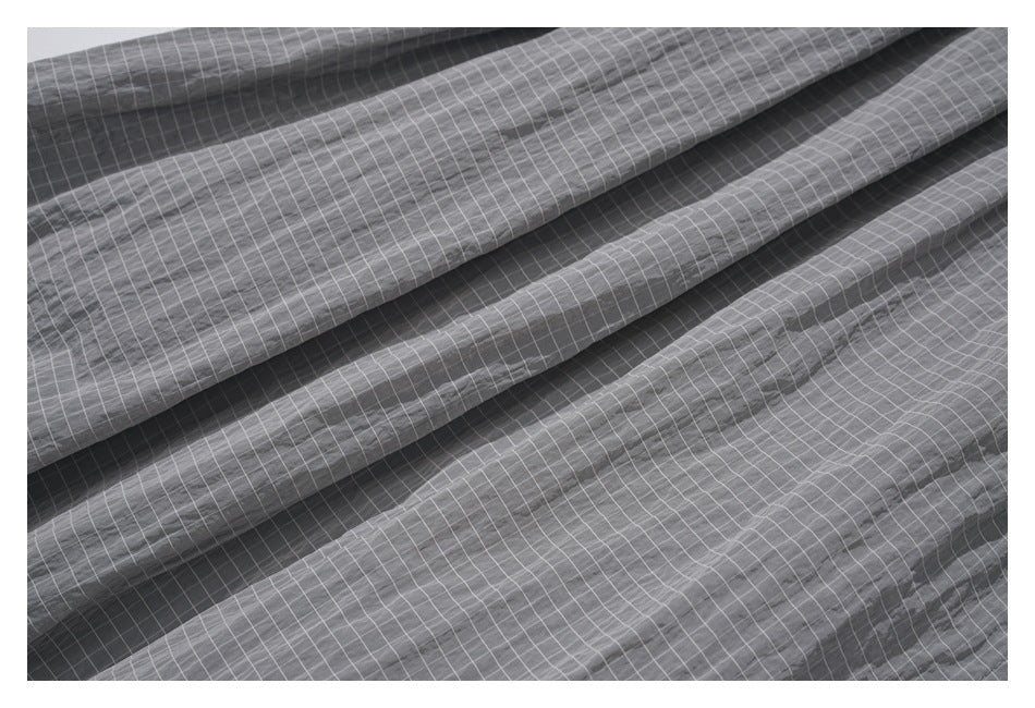 Close-up of folded charcoal-gray fabric with a fine white grid pattern.