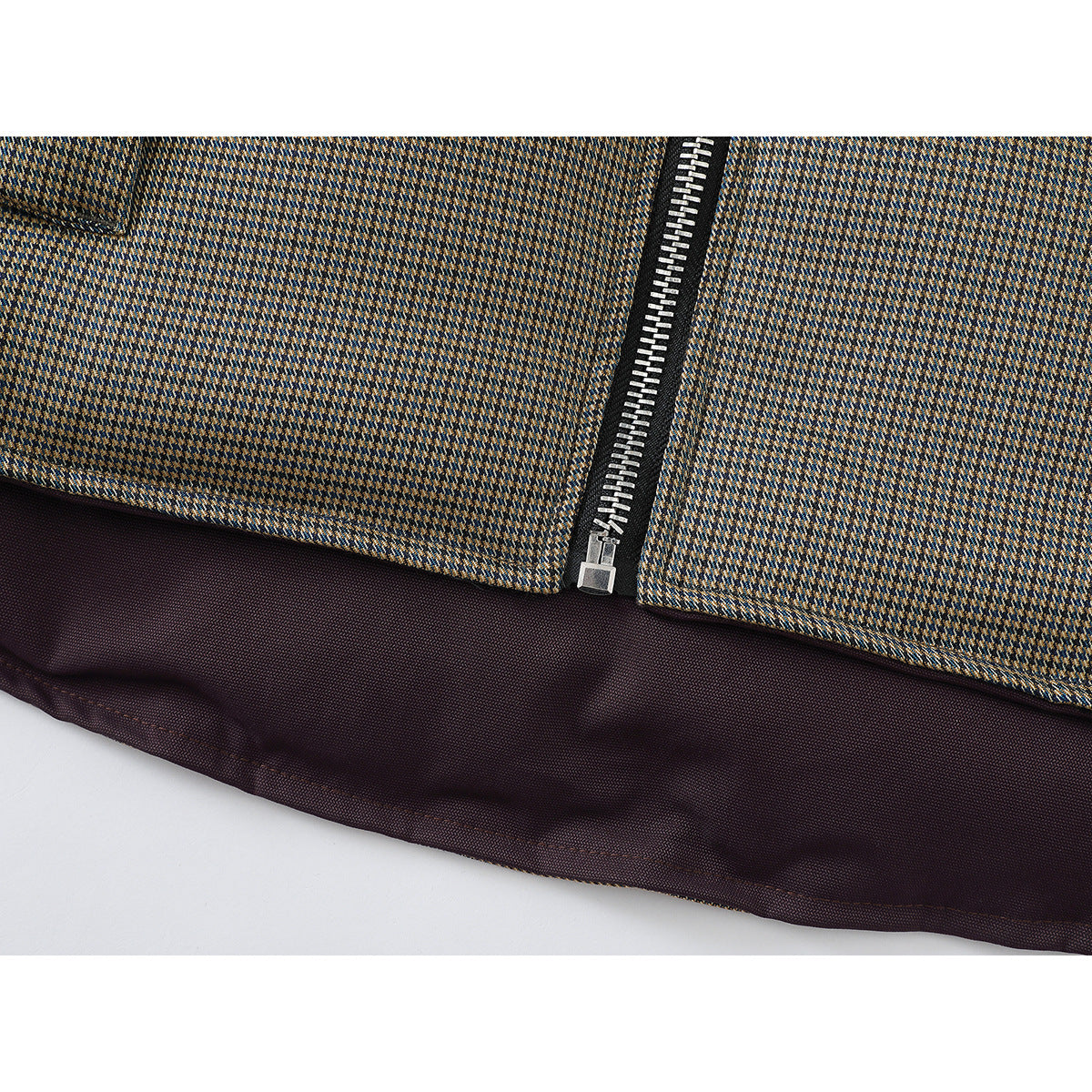 Close-up of the vest's patterned lower front, silver zipper, and dark plum lining at the hem.