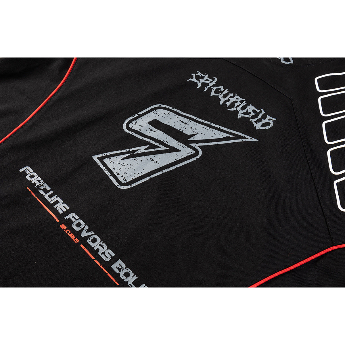 Close-up of a black shirt with distressed gray graphic text and emblem, white outlined shapes, and red piping.