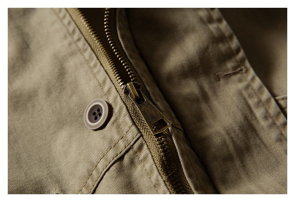 Close-up of the khaki jacket's metal zipper and adjacent button fastening.