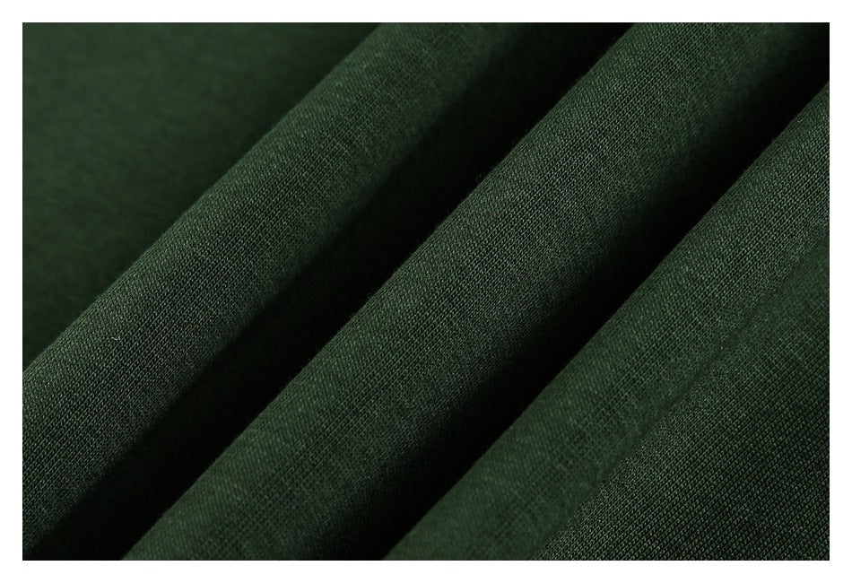 Close-up of dark green fabric draped in folds, showing its knit texture.
