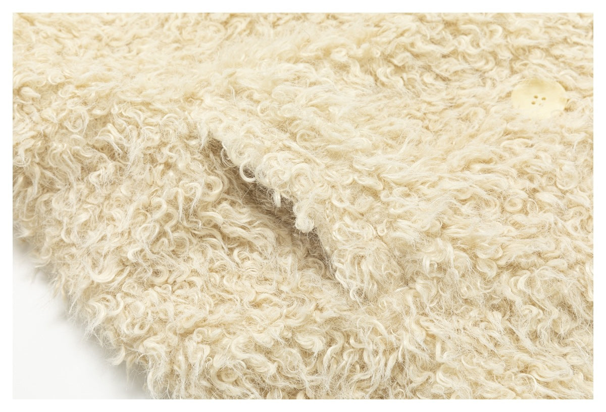 Close-up of cream curly-pile garment fabric with a small pale button near the upper right.