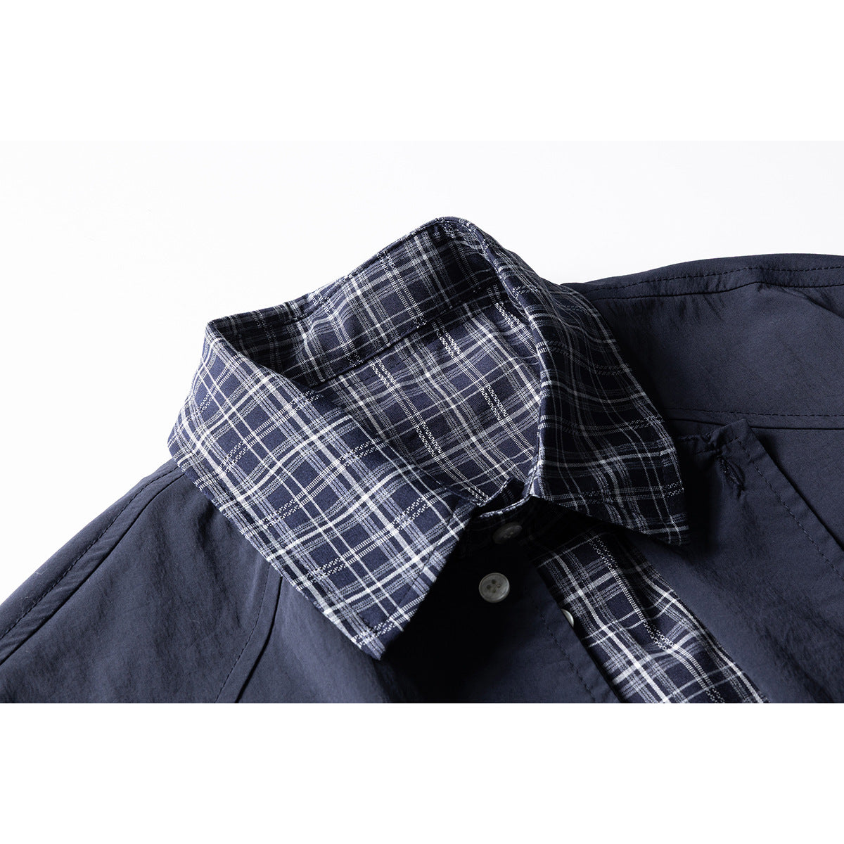 Close-up of a navy shirt with a white-and-gray plaid collar and matching inner placket.