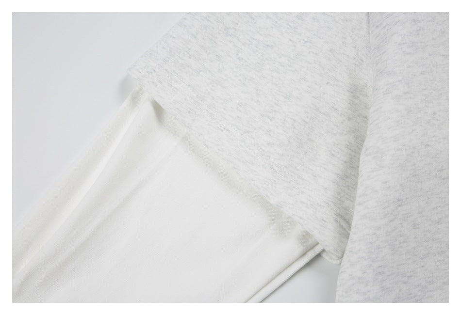 Close-up of the light gray heather shirt’s sleeve and seam beside a section of plain white fabric.